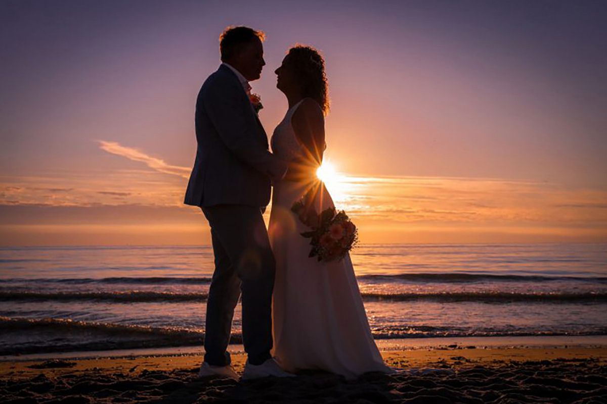 Trouwen op Texel, bruidspaar in silhouet met zonsondergang 